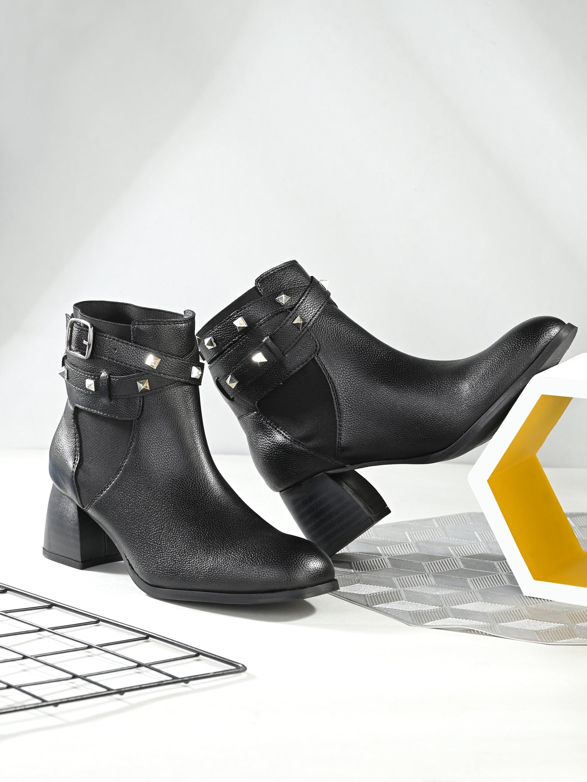 Women Black studded leather ankle boots with studded straps and a buckle design.