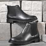 Black leather Classic Chelsea boot with elastic side panels, pull-tab at the heel, rounded toe, and a small metallic brand logo near the ankle.