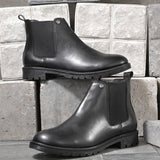 Black leather Classic Chelsea boot with elastic side panels, pull-tab at the heel, rounded toe, and a small metallic brand logo near the ankle.
