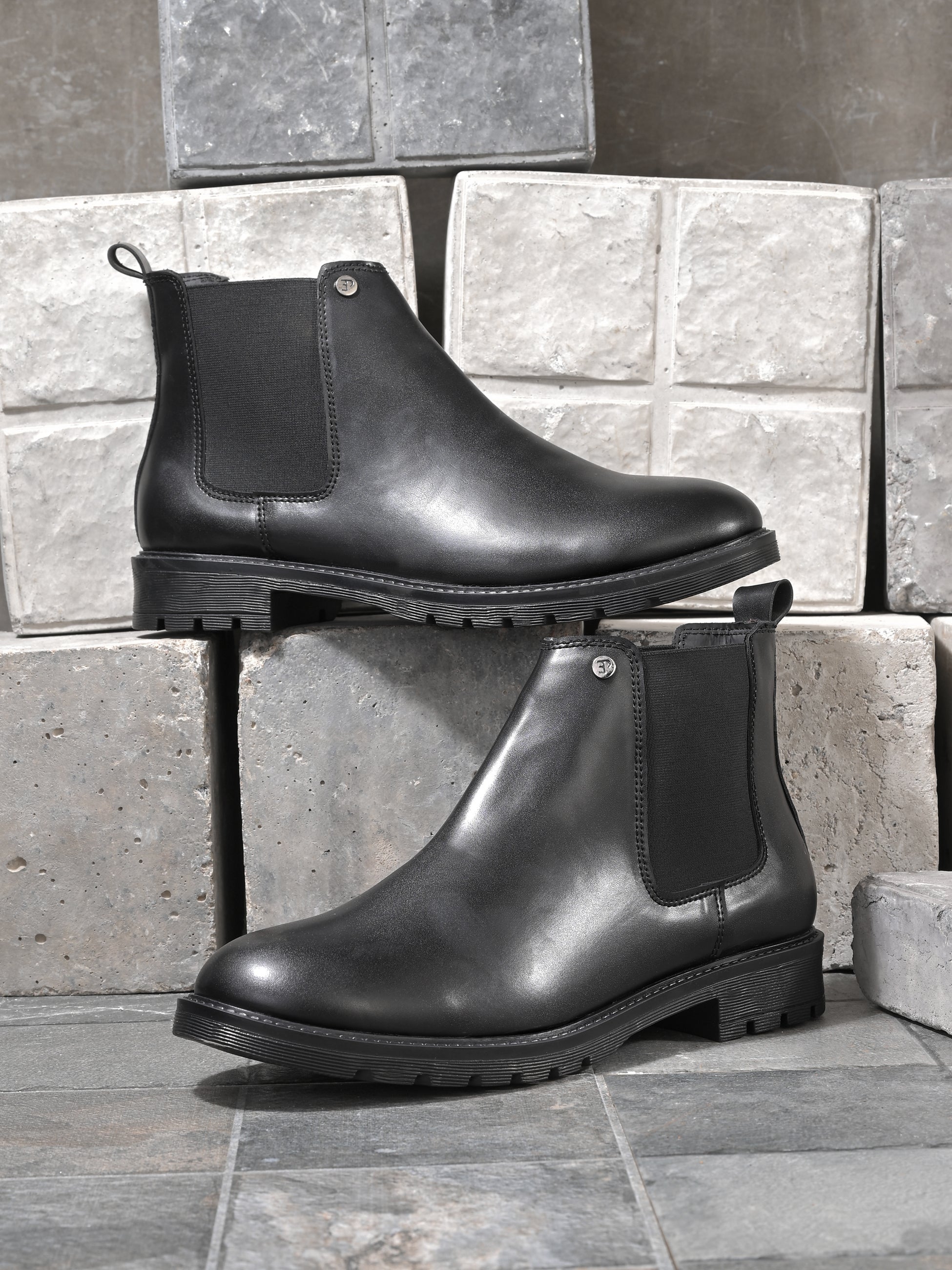 Black leather Classic Chelsea boot with elastic side panels, pull-tab at the heel, rounded toe, and a small metallic brand logo near the ankle.