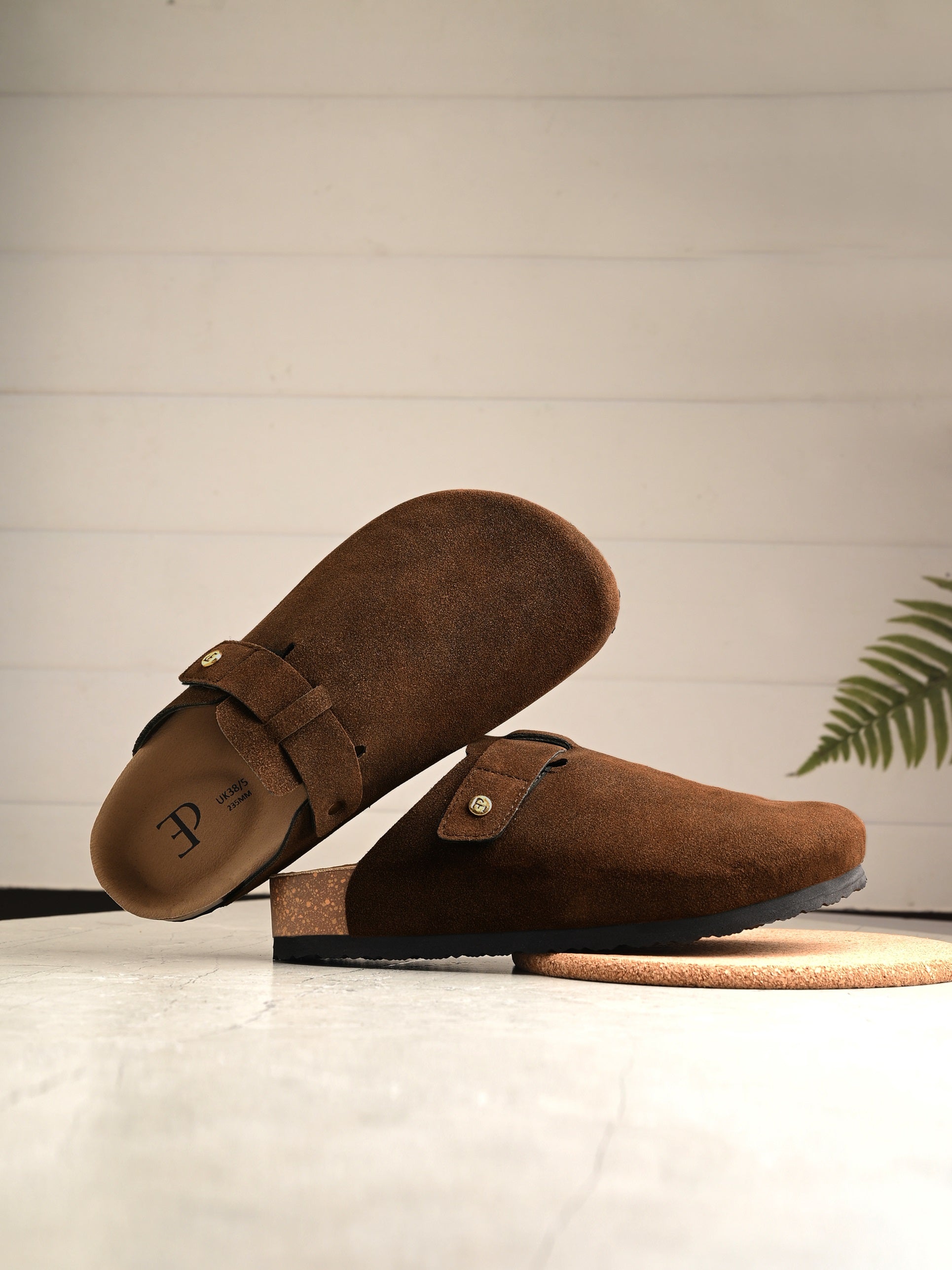 Brown suede slip-on clog with a black rubber sole and adjustable strap.