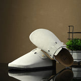 Nude suede slip-on clog with a black rubber sole and adjustable strap.