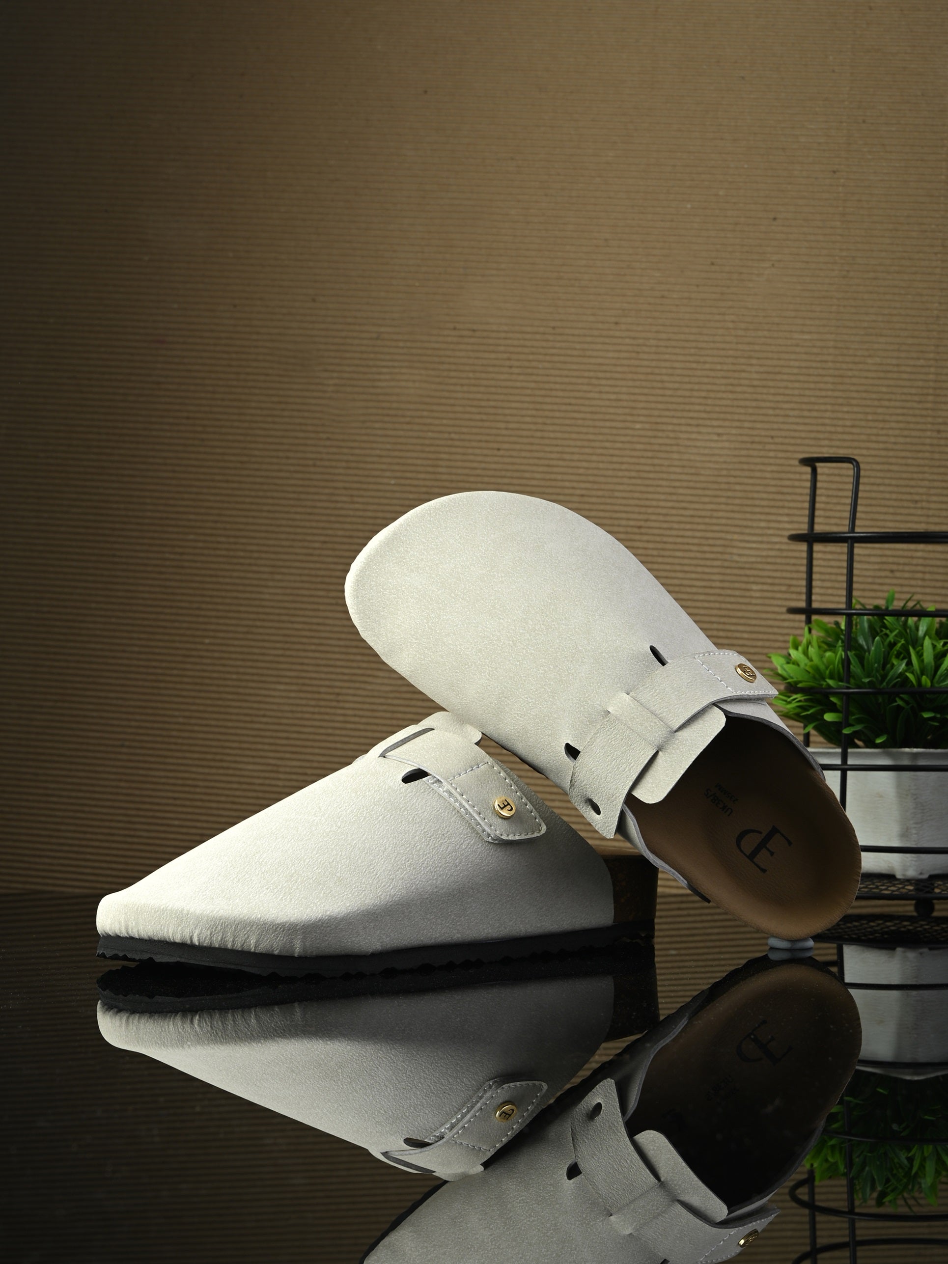 Nude suede slip-on clog with a black rubber sole and adjustable strap.