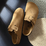 Beige suede slip-on clog with a black rubber sole, adjustable strap, and Boston Soft Footbed for enhanced comfort and support.