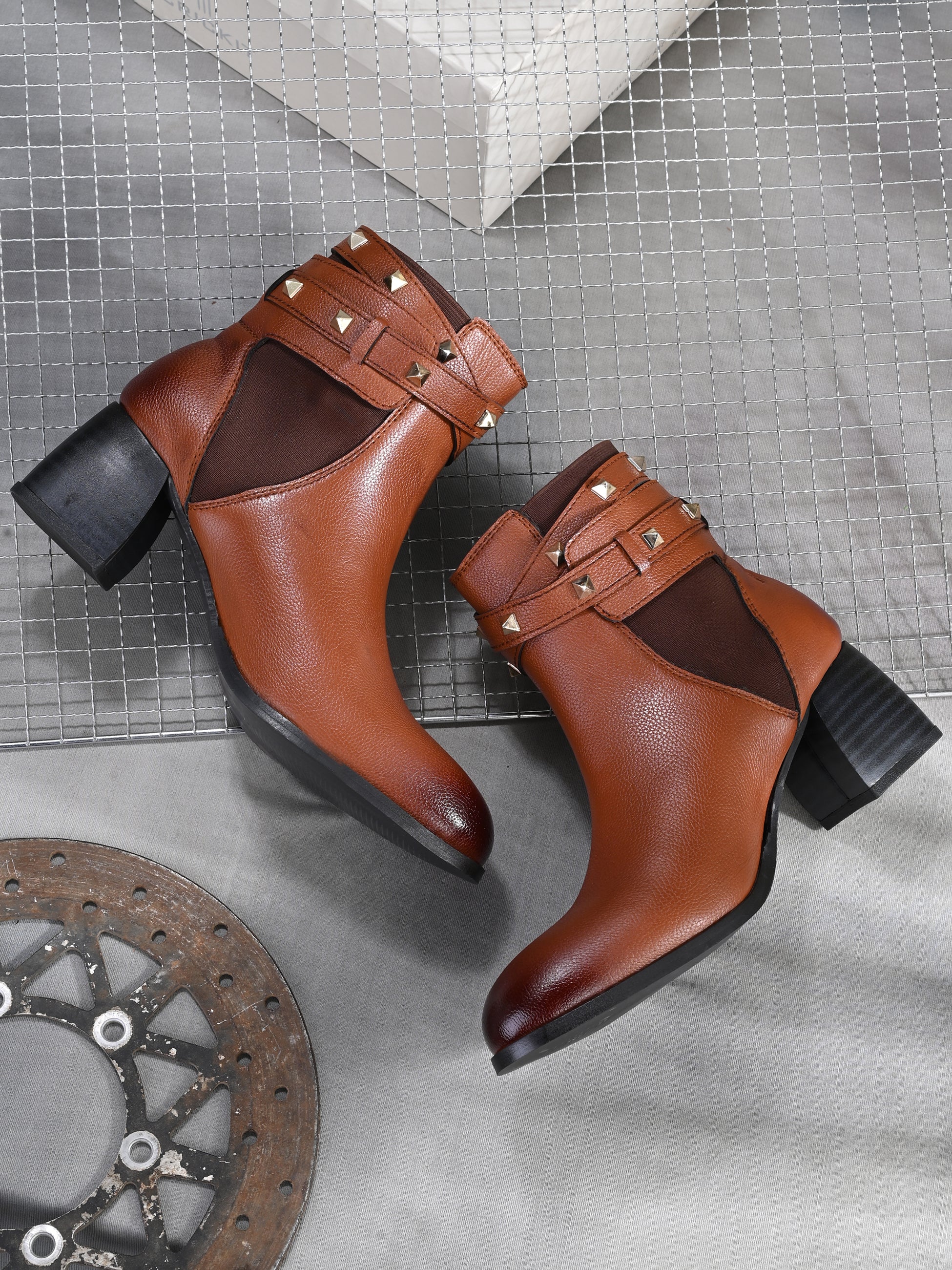 Women brown studded leather ankle boots with studded straps and a buckle design.