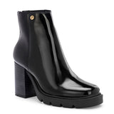 Glossy black patent leather ankle boot with a chunky block heel, lug sole, and a gold logo detail near the collar.