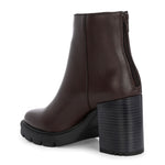 Glossy brown patent leather ankle boot with a chunky block heel, lug sole, and a gold logo detail near the collar.