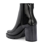 Glossy black patent leather ankle boot with a chunky block heel, lug sole, and a gold logo detail near the collar.