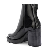 Glossy black patent leather ankle boot with a chunky block heel, lug sole, and a gold logo detail near the collar.