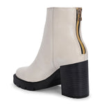 Glossy beige patent leather ankle boot with a chunky block heel, lug sole, and a gold logo detail near the collar.