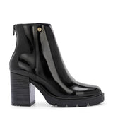 Glossy black patent leather ankle boot with a chunky block heel, lug sole, and a gold logo detail near the collar.