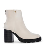 Glossy beige patent leather ankle boot with a chunky block heel, lug sole, and a gold logo detail near the collar.