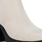 Glossy beige patent leather ankle boot with a chunky block heel, lug sole, and a gold logo detail near the collar.