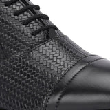 A black formal shoe with a textured pattern, lace-up design, and smooth toe cap.