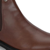 Brown Chelsea boots with elastic side panels, a pull-tab at the heel, rounded toe, and a small metallic brand logo near the ankle.