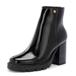 Glossy black patent leather ankle boot with a chunky block heel, lug sole, and a gold logo detail near the collar.
