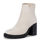 Glossy beige patent leather ankle boot with a chunky block heel, lug sole, and a gold logo detail near the collar.