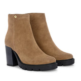 Glossy camel patent leather zip-closure ankle boot with a chunky block heel, lug sole, and a gold logo detail near the collar.