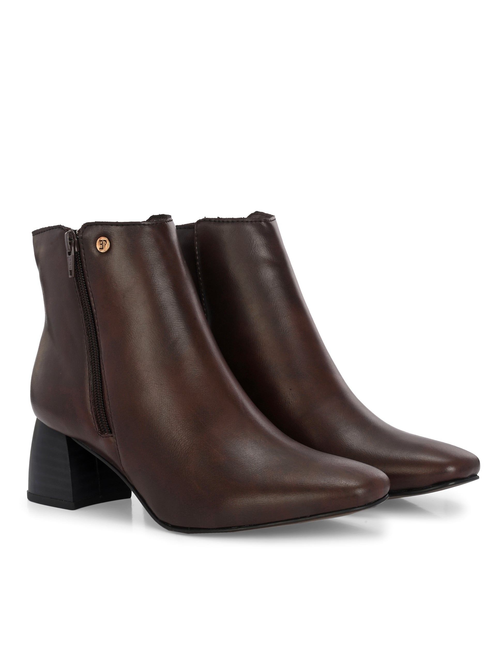 Suede ankle boot with pointed toe, chunky block heel, side zipper, and gold logo detail near the top.