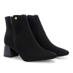 Suede ankle boot with pointed toe, chunky block heel, side zipper, and gold logo detail near the top.