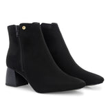 Suede ankle boot with pointed toe, chunky block heel, side zipper, and gold logo detail near the top.