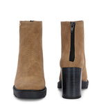 Glossy black patent leather ankle boot with a chunky block heel, lug sole, and a gold logo detail near the collar.