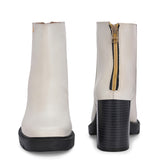 Glossy beige patent leather ankle boot with a chunky block heel, lug sole, and a gold logo detail near the collar.