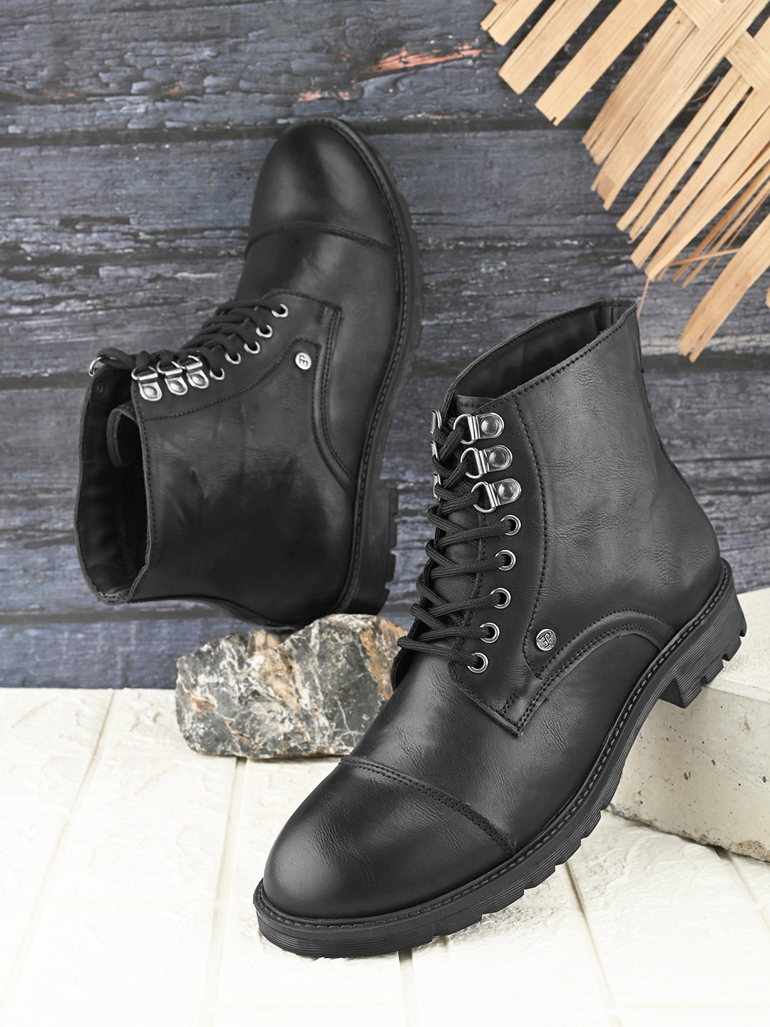 black lace up men boots with cap toe, silver eyelets, grooved rubber sole, and subtle brand logo near the ankle.