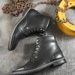 Men's black leather lace-up block-heeled boots with metal eyelets, stitched detailing, and a low heel.