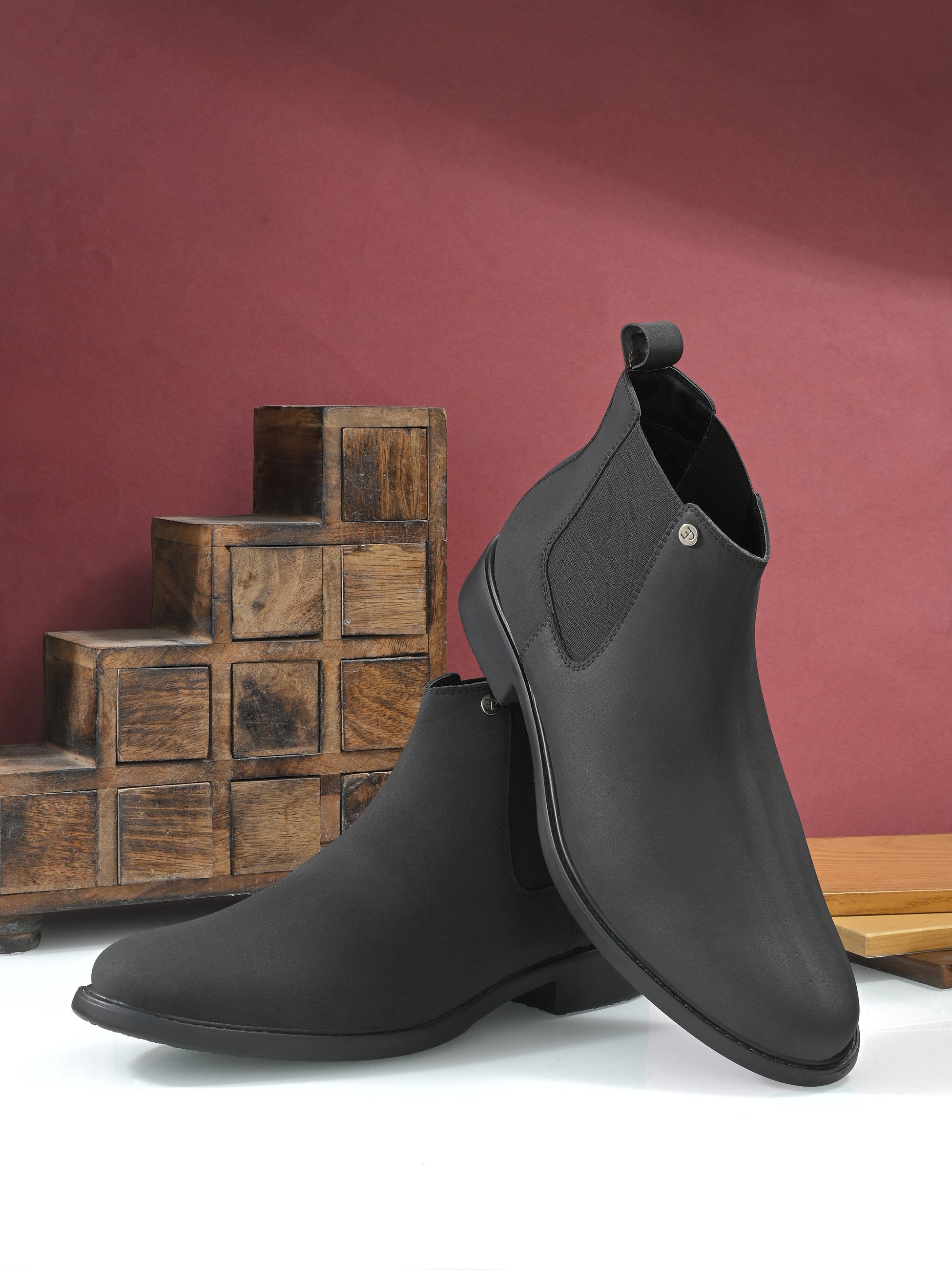 Black Chelsea boots with a matte finish, elastic side panels, pull-tab, and a subtle metallic logo accent.