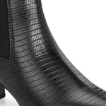 A stylish black ankle boot with a smooth leather finish, almond-shaped toe, mid-block heel, elastic side panel, and a gold accent logo.