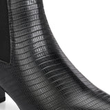 A stylish black ankle boot with a smooth leather finish, almond-shaped toe, mid-block heel, elastic side panel, and a gold accent logo.