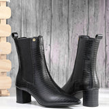 A sleek black crocodile-textured ankle boot with a pointed toe and mid-block heel, featuring an elastic side panel and a gold accent logo.