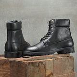 Men's black high-top lace-up boots with textured leather, padded collar, metal eyelets, and a rugged sole.