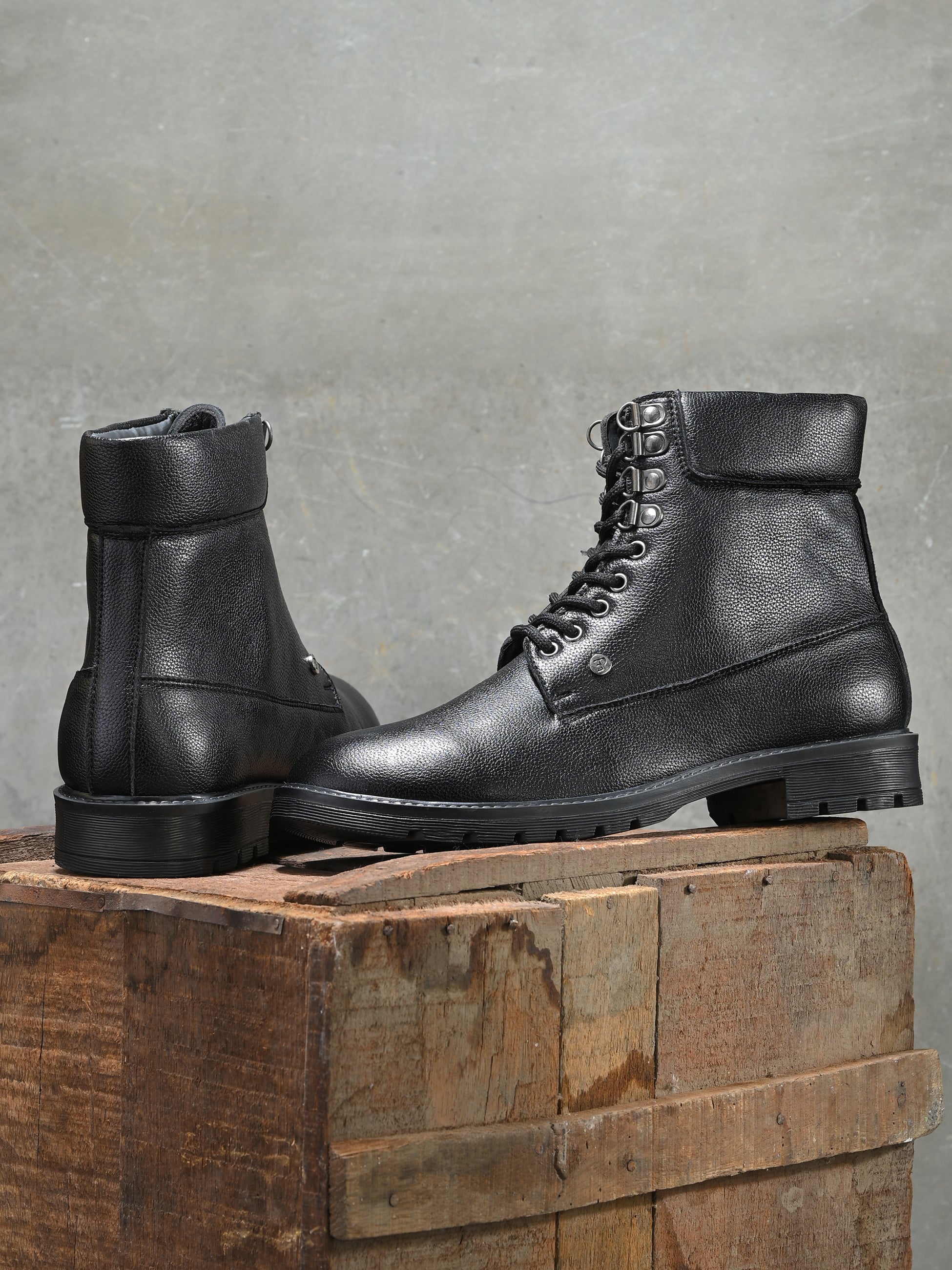 Men's black high-top lace-up boots with textured leather, padded collar, metal eyelets, and a rugged sole.