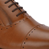 A brown leather dress shoe with a lace-up design, featuring decorative perforations along the toe cap and sides, and a low black heel.