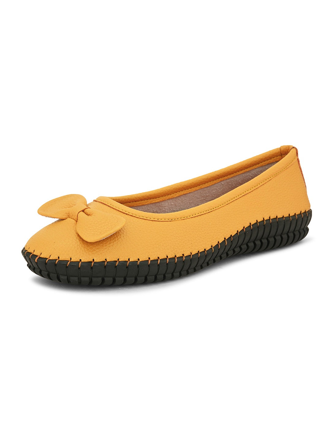 Mustard yellow leather flat shoe with a decorative bow, black textured sole, and visible stitching for a casual, stylish look.
