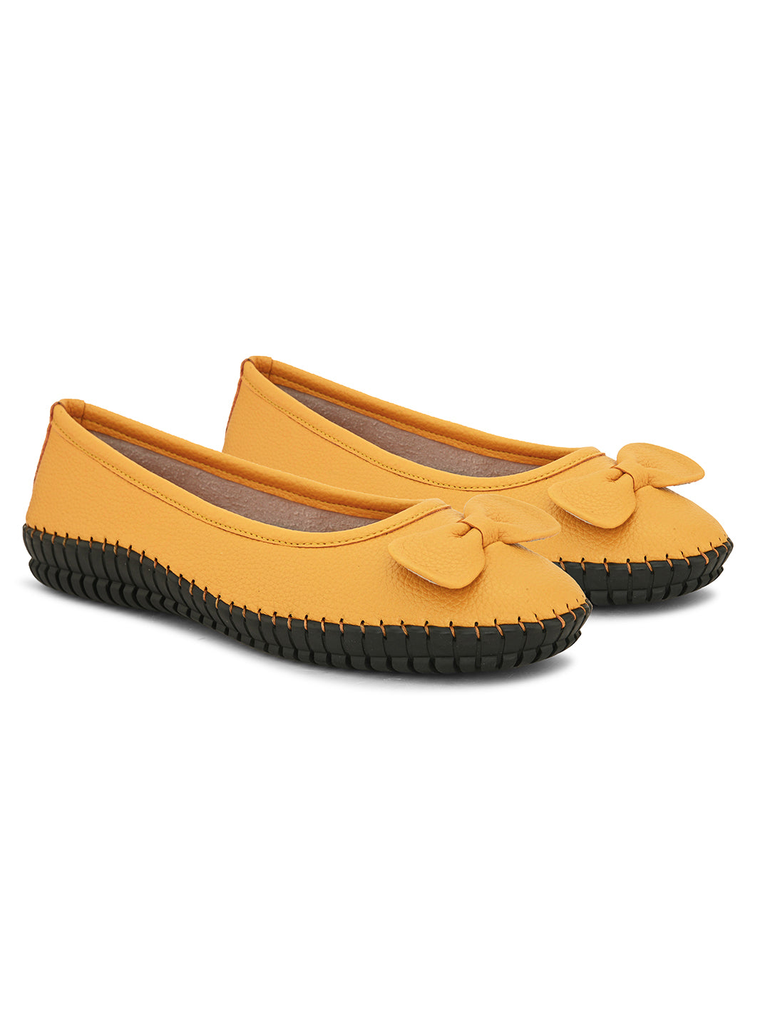 Mustard yellow leather Women Ballerina Flats with a decorative bow, black textured sole, and visible stitching for a casual, stylish look.
