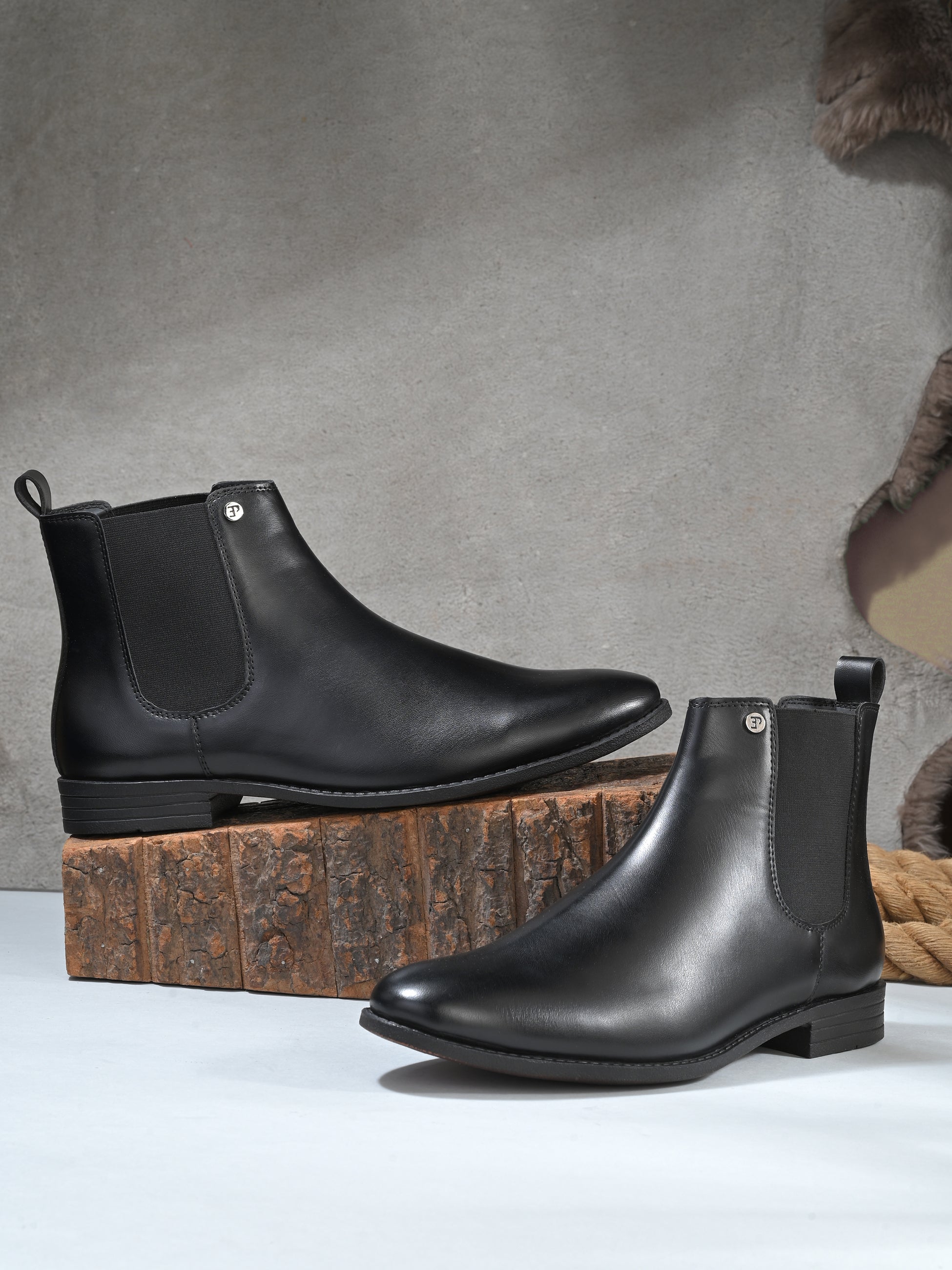 A sleek black leather Chelsea boot for women with elastic side panels, pull tab, low stacked heel, and a polished finish, offering a versatile style like the Men Faux Leather Casual Chelsea Boots.