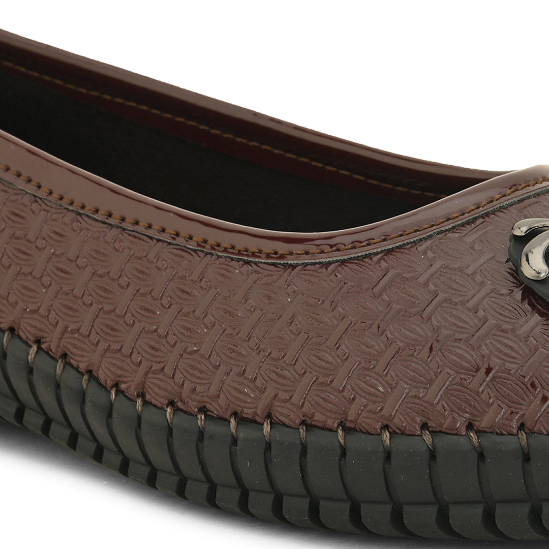 A brown woven-texture flat shoe with a round metal ornament on the toe and a black rubber sole.