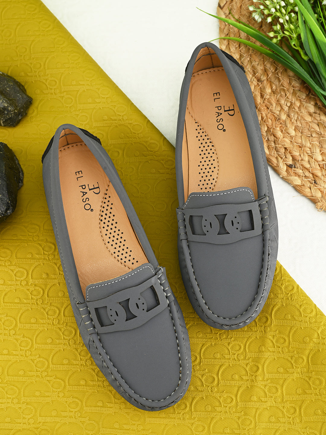 A gray loafer for women with textured stitching and a decorative strap across the top, viewed from the side.